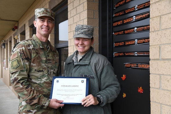 Col. Richard Tanner, 22nd Air Refueling Wing commander, awards Airman 1st Class Ciera King, 22nd Forces Support Squadron Military Personnel Flight personnelist, a certificate for winning the McConnell Dormitory Door Decorating Contest Oct. 30, 2019, at McConnell Air Force Base, Kan. The three winners selected by Tanner and Chief Master Sgt. Melissa Royster, 22nd ARW command chief, received a day off, a congratulatory certificate and a basket of candy put together by the Airman and Family Readiness Center. (U.S. Air Force photo by Airman 1st Class Nilsa E. Garcia)