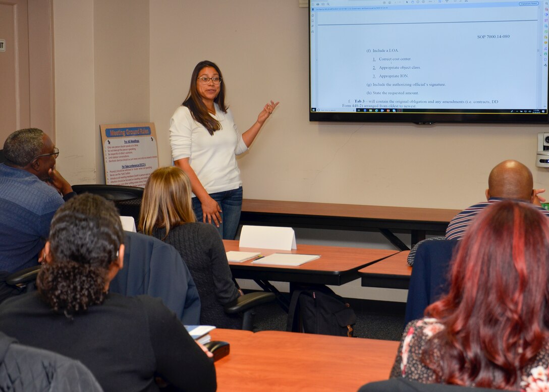 Crystal Leija stands in front of a group of people sitting at tables and leads a workshop topic.