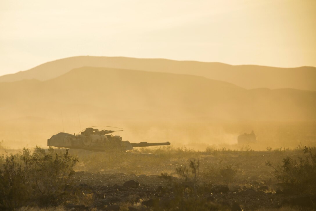 A tank moves through desert terrain.