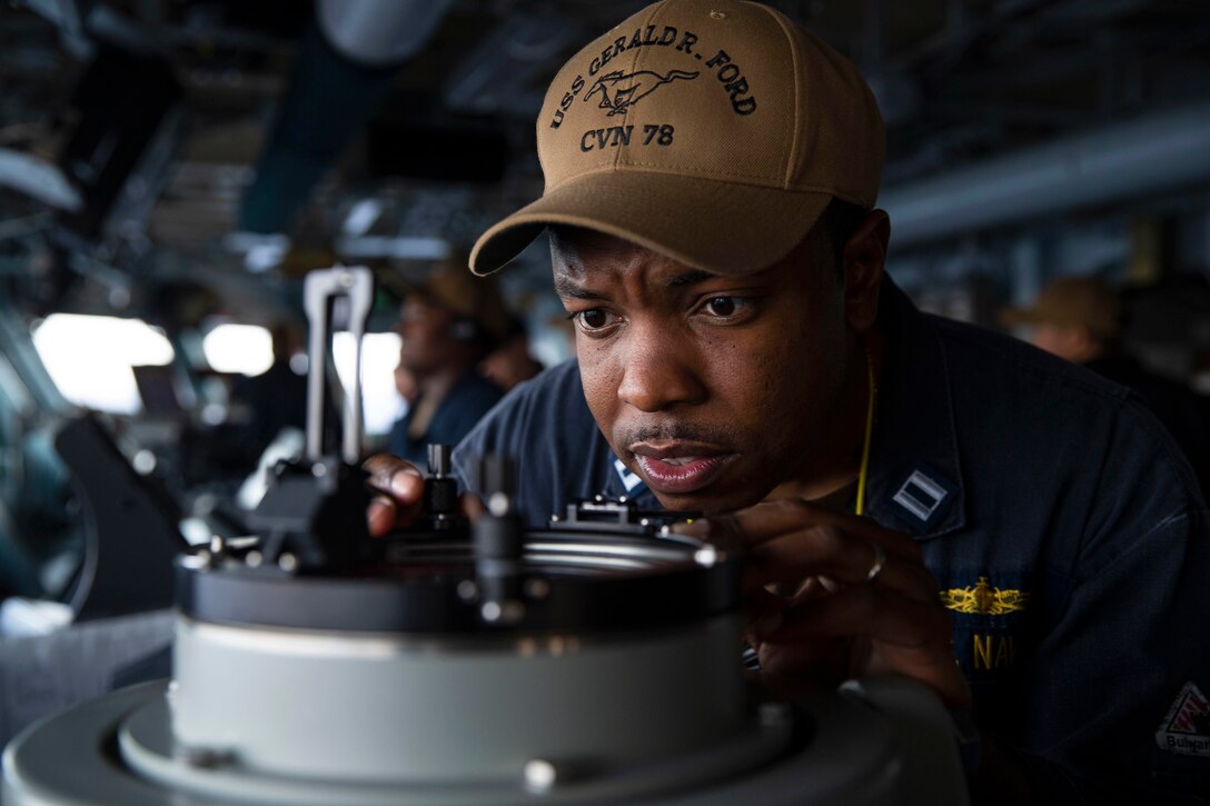 A sailor looks at a bearing aboard a ship.