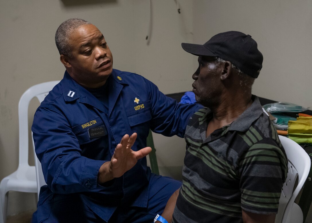 A doctor attached to the hospital ship USNS Comfort (T-AH 20), consults a man about his back pain.