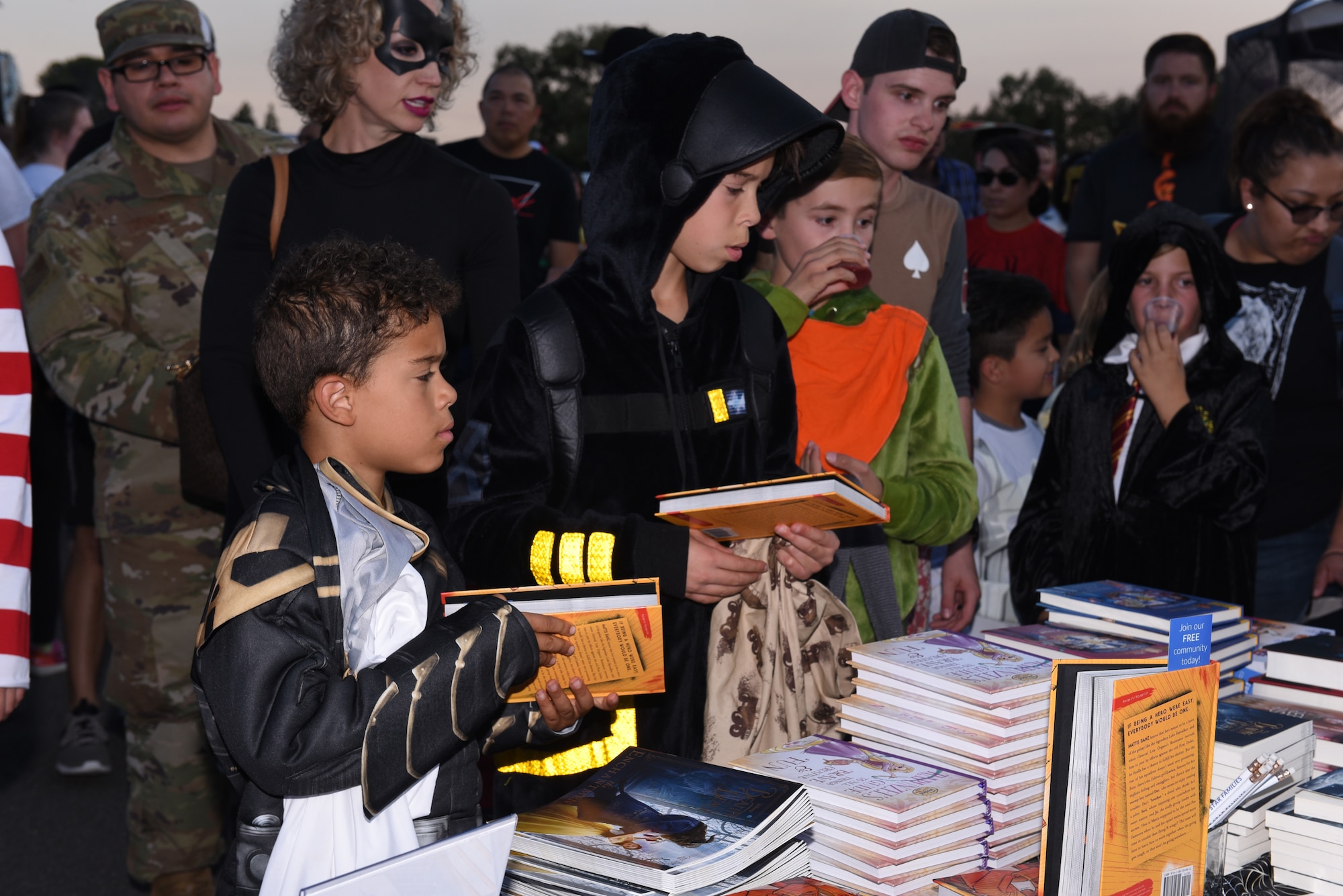Children attending the Trunk-or-Treat event visit a table giving away books from the Airman and Family Readiness Center Oct. 25, 2019, at Travis Air Force Base, California. The Airman and Family Readiness Center hosted Trunk-or-Treat, an annual event aimed to provide a safe place for military families to enjoy Halloween festivities. The event had approximately 5,000 attendees and more than 60 vehicle trunks loaded with candy. (U.S. Air Force photo by Airman 1st Class Cameron Otte)
