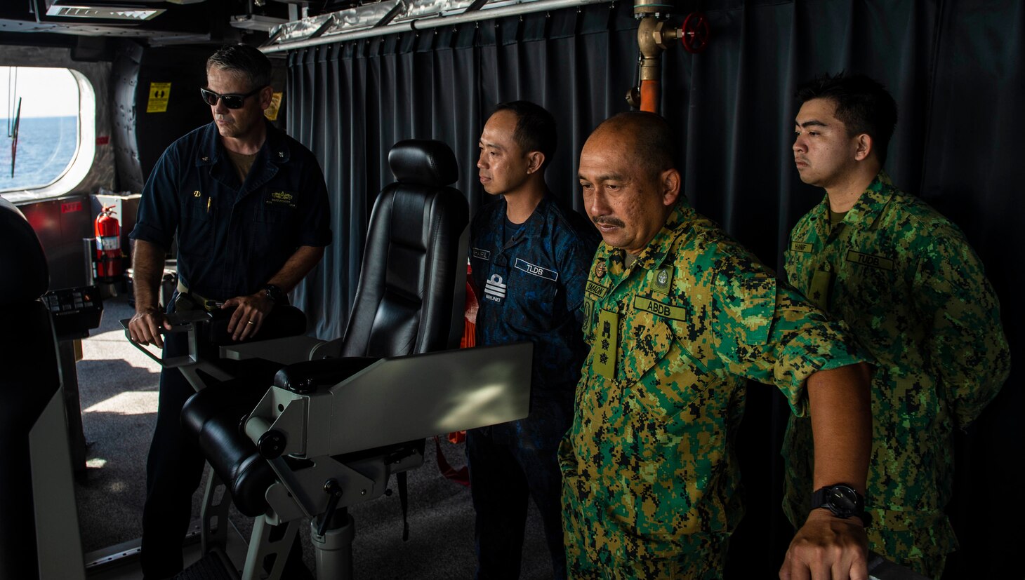 SOUTH CHINA SEA (Oct. 30, 2019) Cmdr. Matthew Richter, commanding officer of the Independence-variant littoral combat ship USS Montgomery (LCS 8) Gold Crew, provides a tour of the bridge to Royal Brunei Armed Forces during Cooperation Afloat Readiness and Training (CARAT) Brunei. This year marks the 25th iteration of CARAT, a multinational exercise designed to enhance U.S. and partner navies' abilities to operate together in response to traditional and non-traditional maritime security challenges in the Indo-Pacific region.