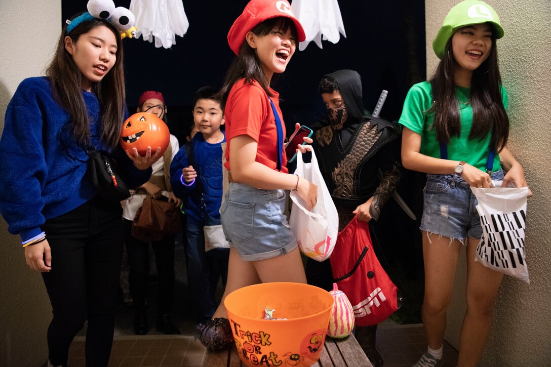 Okinawan children laugh after receiving candy during a Halloween trick-or-treat event Oct. 31, 2019, on Kadena Air Base, Japan. The event enabled service members to share traditional holiday customs with children from surrounding neighborhoods as one of many different types of community relations programs designed to build trust and understanding between U.S. and Japanese culture. (U.S. Air Force photo by Senior Airman Rhett Isbell)