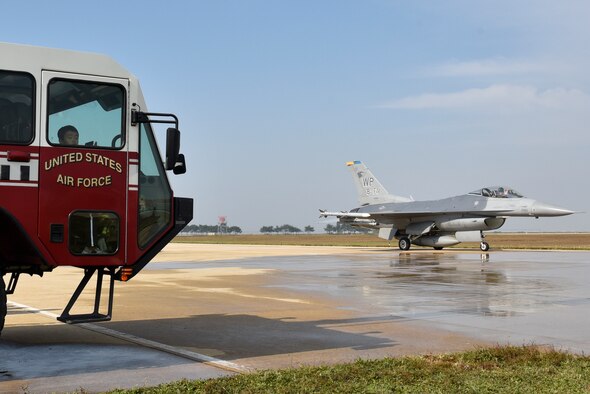 A U.S. Air Force F-16 Fighting Falcon aircraft from the 8th Fighter Wing passes students from the Gunsan Mun Hwa Elementary School during their visit to the 8th Civil Engineer Squadron fire department open house at Kunsan Air Base, Republic of Korea, Oct. 16, 2019. Fire department personnel provided the students with a tour of the fire house, showed them the equipment used to fight fires and taught basic fire safety skills. (U.S. Air Force photo by Tech. Sgt. Joshua Arends)