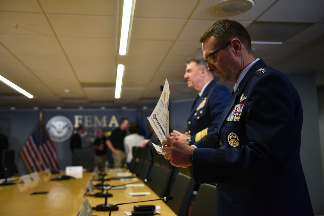 Four-star general in dress uniform reviews information before a briefing.