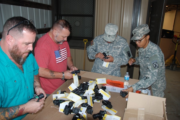 Two soldiers and two civilians checking over excess equipment ready for turn-in.