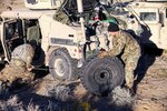Two soldiers changing a tire on a Humvee.