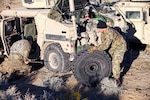 Two soldiers changing a tire on a Humvee.