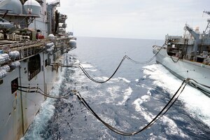 Image of two navy ships at sea with fuel resupply lines running between the two ships.