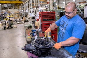 Image of worker using screwdriver to tighten screws on axel assembly in warehouse location.