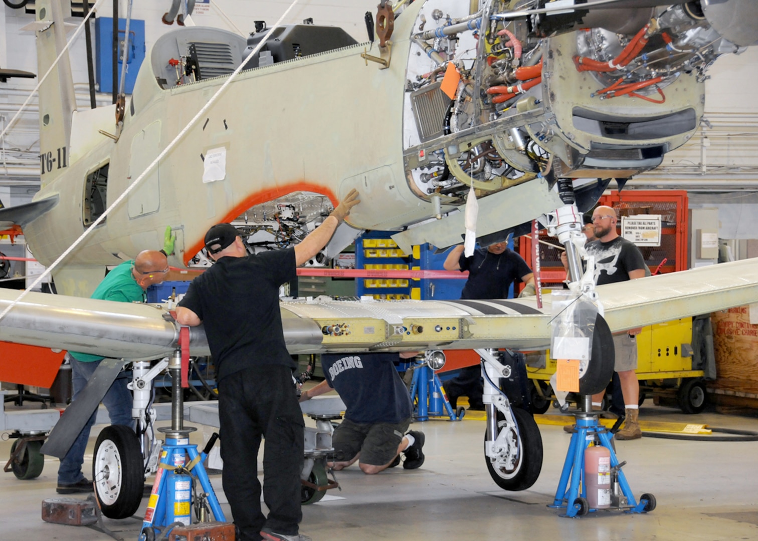 Image of four workers placing wing assembly onto airplane body.