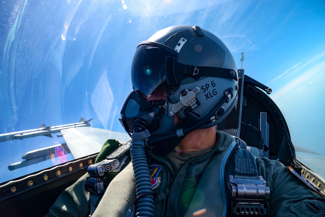 An airman looks out the window of an aircraft.