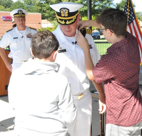 IMAGE: DAHLGREN, Va. (Aug. 30, 2019) – Quinn and Elijah Plew attach new shoulder boards on their father, Capt. Casey Plew, during his promotion ceremony at Naval Surface Warfare Center Dahlgren Division (NSWCDD). It was Plew’s second ceremony marking a career milestone in four months. The new Navy captain took command of NSWCDD – the Naval Sea System Command’s largest Naval Warfare Center – at a ceremony held on the Potomac River Test Range in April.