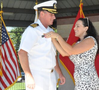 IMAGE: DAHLGREN, Va. (Aug. 30, 2019) – Carolina Plew pins a new name tag on her husband, Capt. Casey Plew, during his promotion ceremony at Naval Surface Warfare Center Dahlgren Division (NSWCDD). It was Plew’s second ceremony marking a career milestone in four months. The new Navy captain took command of NSWCDD – the Naval Sea System Command’s largest Naval Warfare Center – at a ceremony held on the Potomac River Test Range in April.