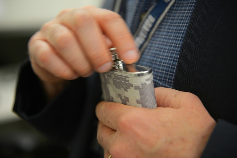 A hand manipulates the cap on a flask.