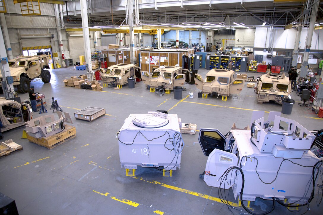 Image of warehouse action with MRAP parts placed in bays.