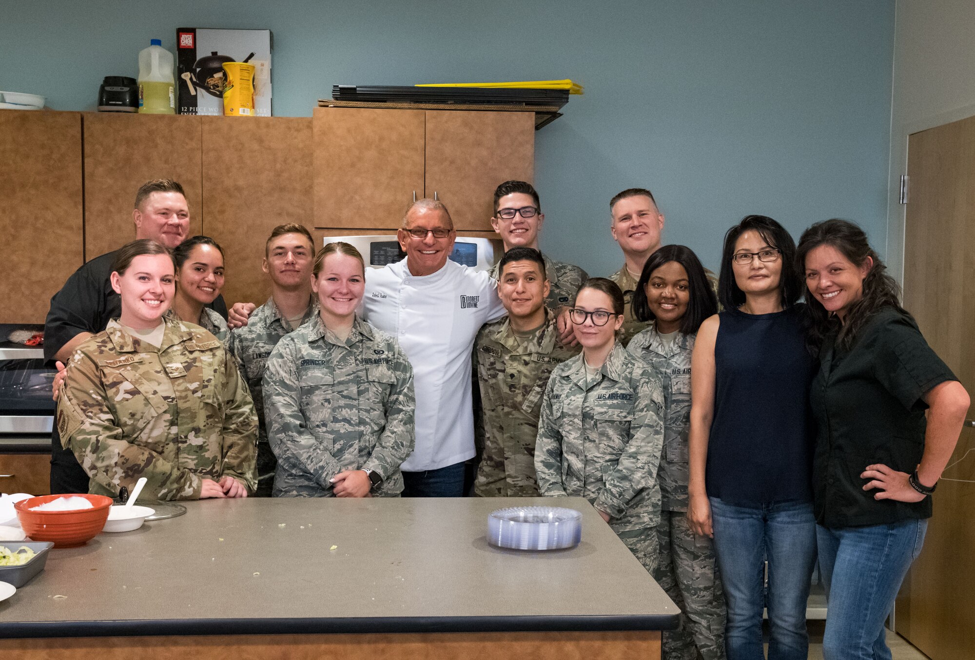 Chef Robert Irvine and his corporate chef, Shane Cash, along with Dorm to Gourm students pose for a photo, Aug. 27, 2019, at the Fitness Center on Dover Air Force Base, Del. Irvine taught Team Dover members how to make Cuban-Style Stewed Chicken Ropa Vieja Street Tacos and Rad Na Thai Chicken Salad. (U.S. Air Force photo by Roland Balik)
