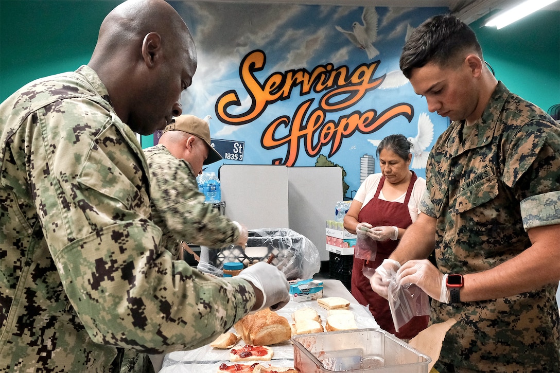 Service members prepare meals at a table.