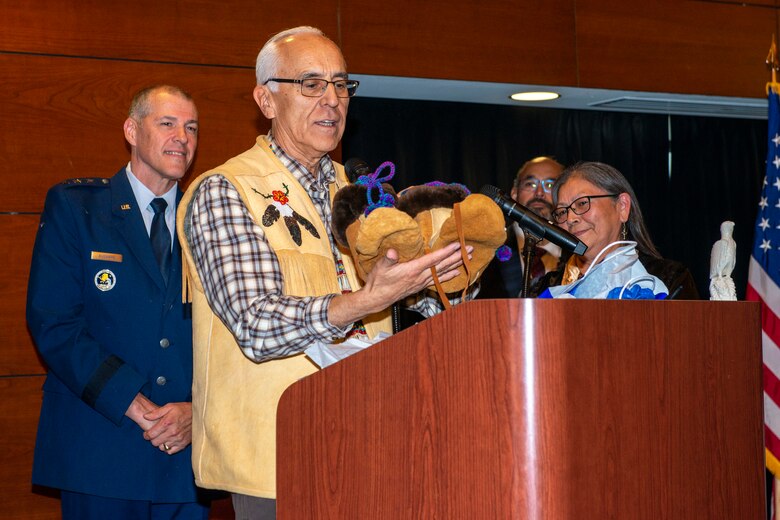Will Mayo, Alaska Federation of Natives co-chair and Tanana Chiefs Conference member, describes a gift to be presented to U.S. Air Force Lt. Gen. Thomas Bussiere, commander, Alaskan North American Aerospace Defense Command Region, North American Aerospace Defense Command; commander, Alaskan Command, U.S. Northern Command; and commander, 11th Air Force, Pacific Air Forces, during an Alaska Native naming ceremony on Joint Base Elmendorf-Richardson, Alaska, Aug. 28, 2019. The AFN hosted the event honoring Bussiere for his service and his active engagement with the Alaska Native community during his tenure in Alaska. The naming ceremony is based on the traditional belief that a person’s name is the type of soul they possess. The ceremony showcased the bond between the Alaska Native community and the military in Alaska.