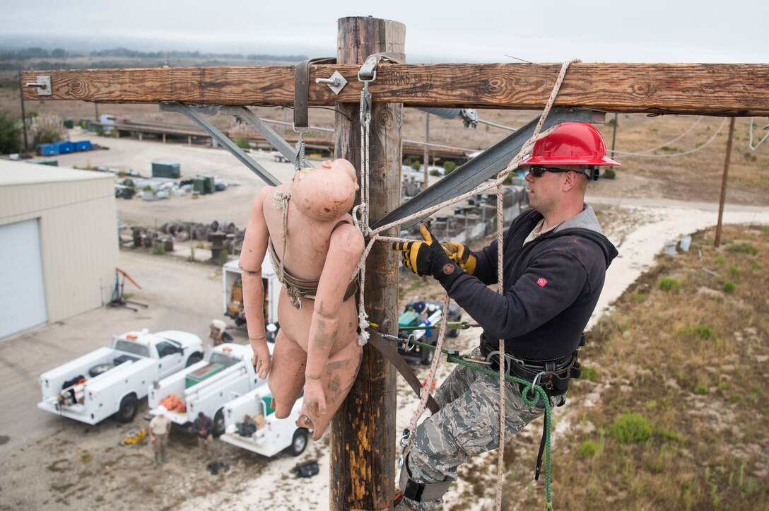 Senior Airman Rafal Waledziak, 30th Civil Engineer Squadron electrician, retrieves a dummy from atop a power pole during pole-top rescue training Aug. 23, 2019, at Vandenberg Air Force Base, Calif. During the training, each service member had four minutes to climb a power pole, retrieve a dummy, and hoist the dummy safely to the ground. The Airmen utilize this training to learn the techniques necessary to perform emergency pole-top rescues.  (U.S. Air Force photo by Hanah Abercrombie)