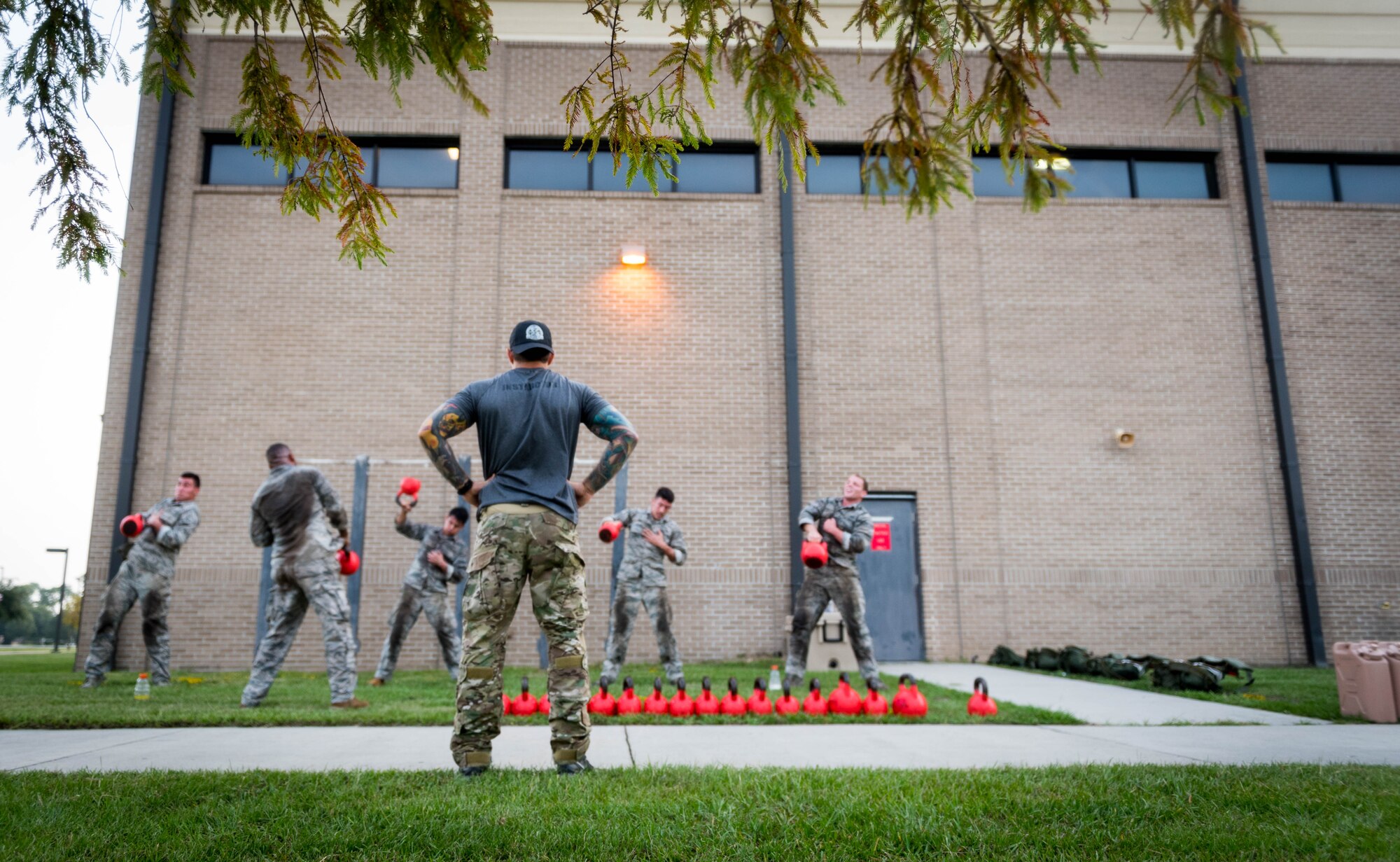 A 352nd Special Warfare Squadron training instructor looks on as Airmen from the 352nd SWTS participate in a memorial physical training session outside of Matero Hall on Keesler Air Force Base, Mississippi, Aug. 9, 2019. The PT event was in memory of U.S. Air Force Staff Sgt. Andrew Harvell, combat controller, who was killed in action on Aug. 6, 2011. Special Warfare trainees also attend courses in the 334th and 335th Training Squadrons. (U.S. Air Force photo by Sarah Loicano)