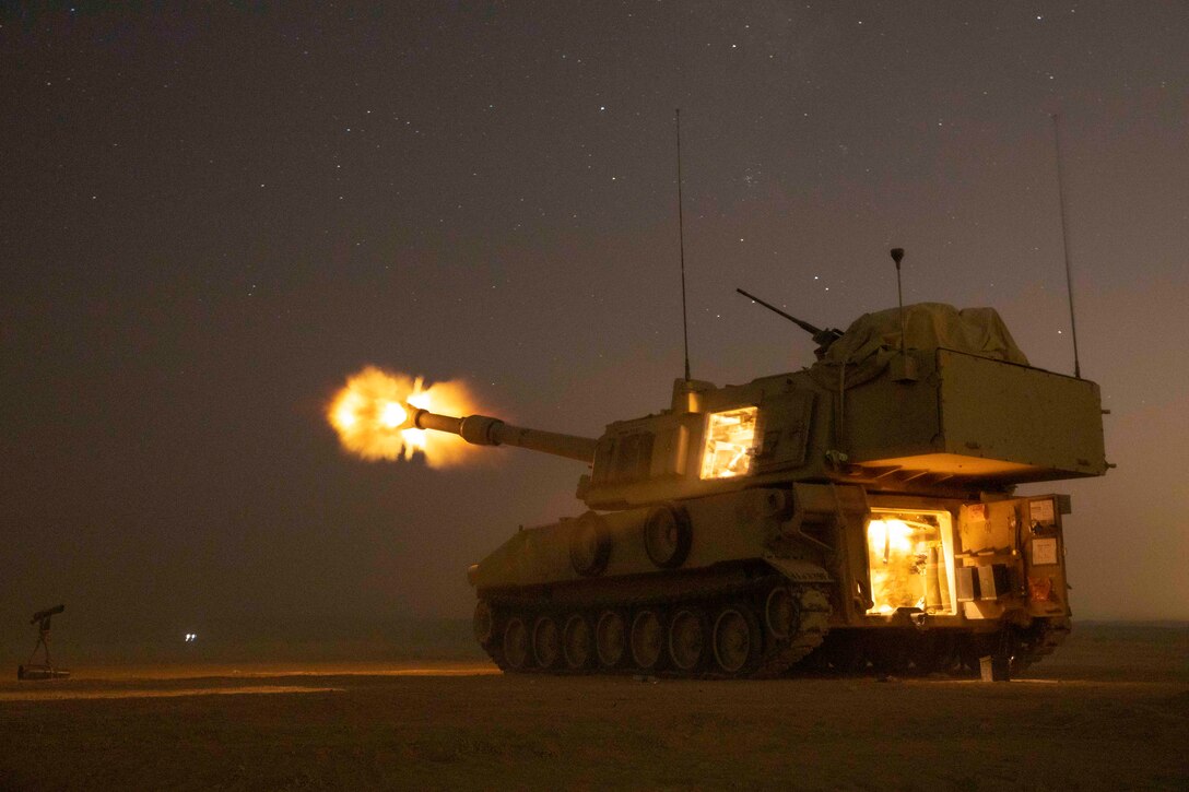 A howitzer firing at night.