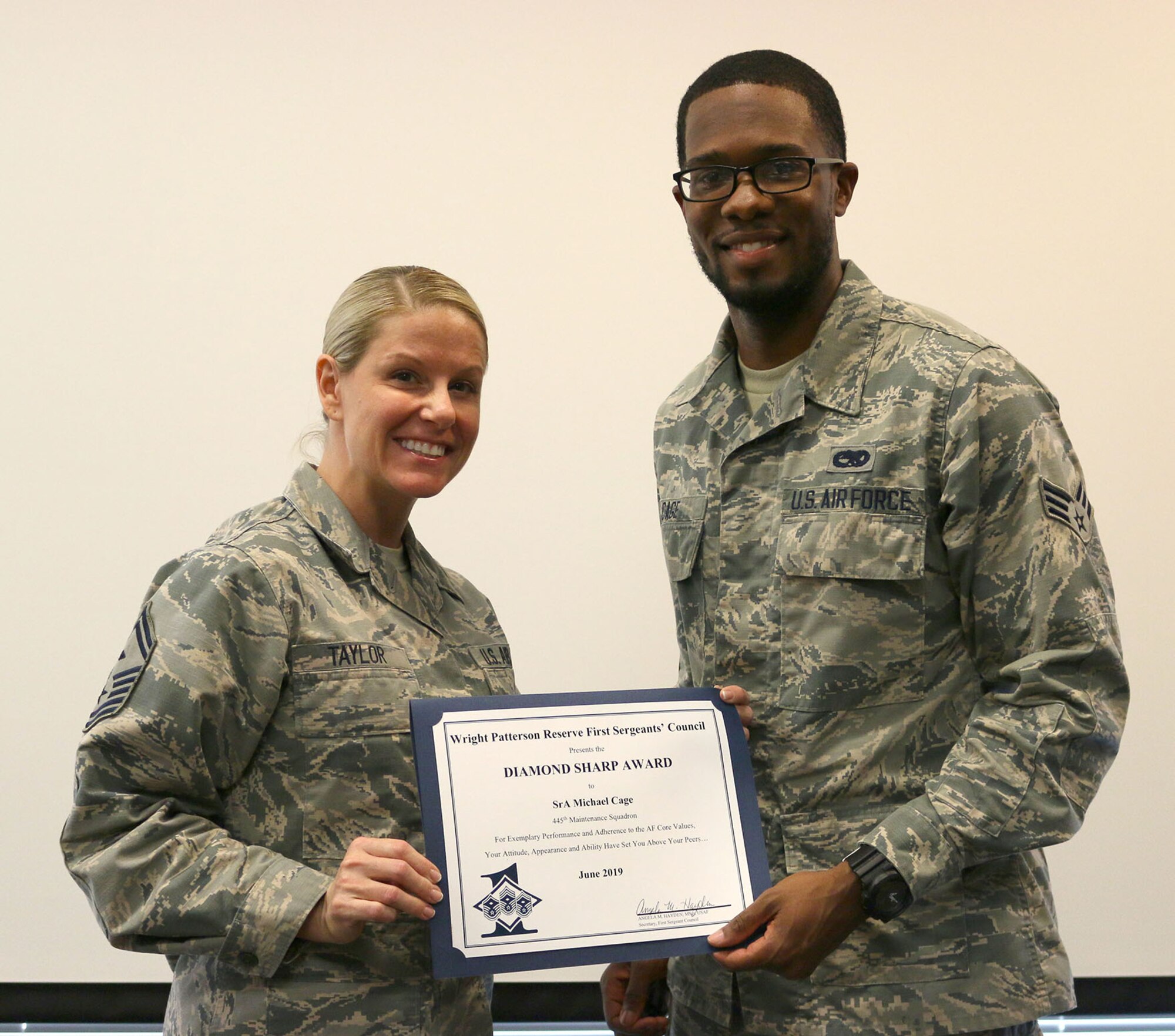 Senior Master Sgt. Lauren Taylor, 445th Maintenance Squadron first sergeant, presents the June 2019 Diamond Sharp Award to Senior Airman Michael Cage, 445th MXS, during the August 17, 2019, unit training assembly.  The award is for exemplary performance, adherence to the Air Force Core Values, attitude, appearance and ability. (U.S. Air Force photo/Staff Sgt. Joel McCullough)