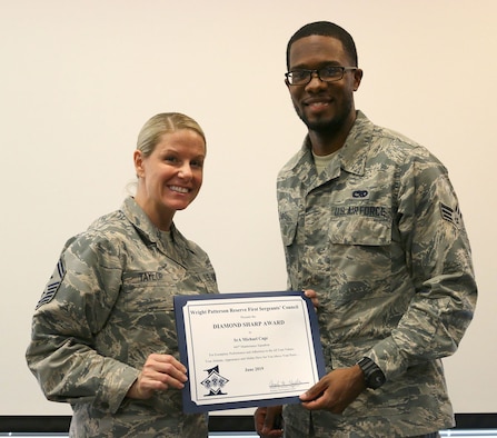Senior Master Sgt. Lauren Taylor, 445th Maintenance Squadron first sergeant, presents the June 2019 Diamond Sharp Award to Senior Airman Michael Cage, 445th MXS, during the August 17, 2019, unit training assembly.  The award is for exemplary performance, adherence to the Air Force Core Values, attitude, appearance and ability. (U.S. Air Force photo/Staff Sgt. Joel McCullough)