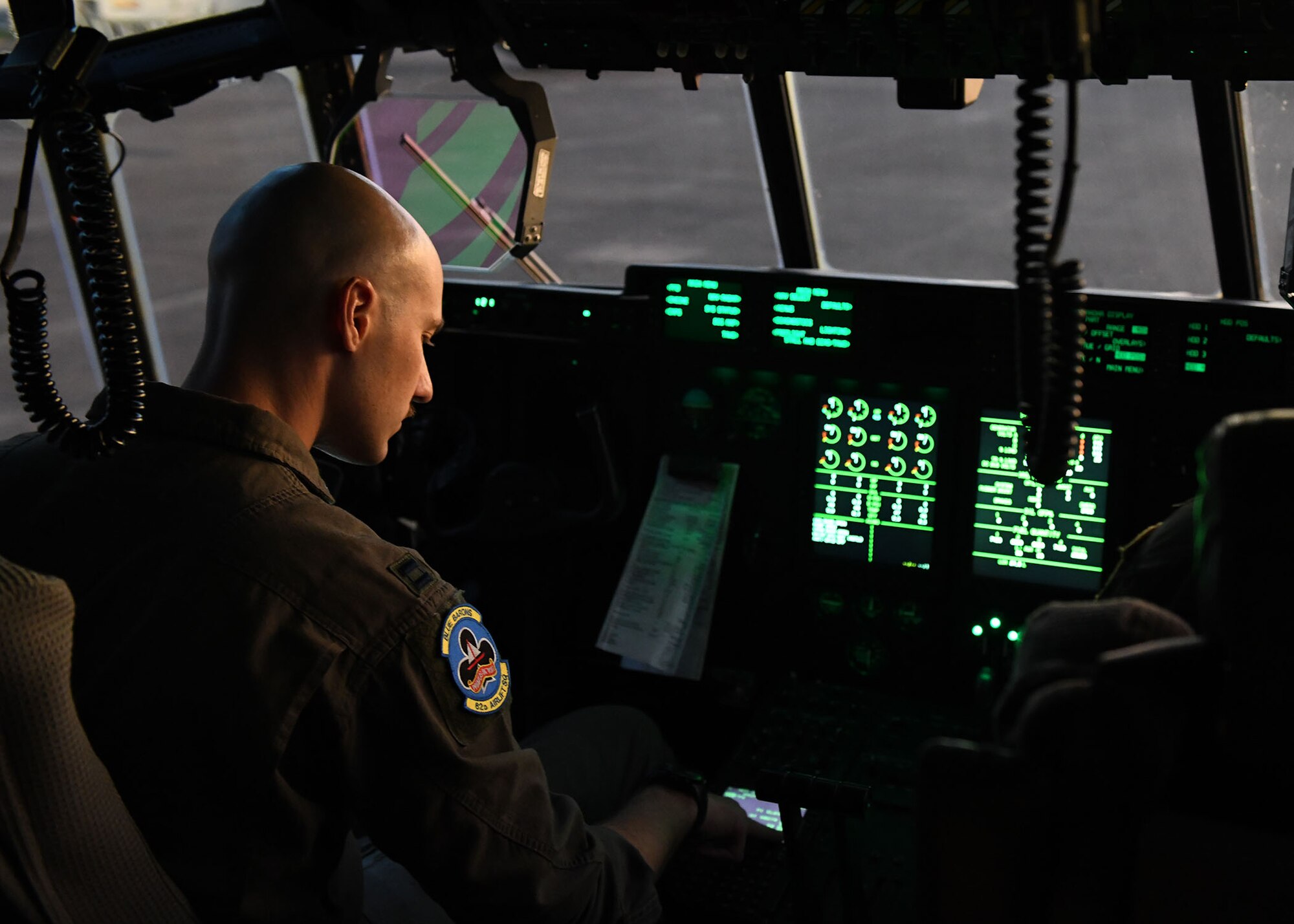 A man looks at a piece of paper that is clipped on the dashboard inside the cockpit of an airplane