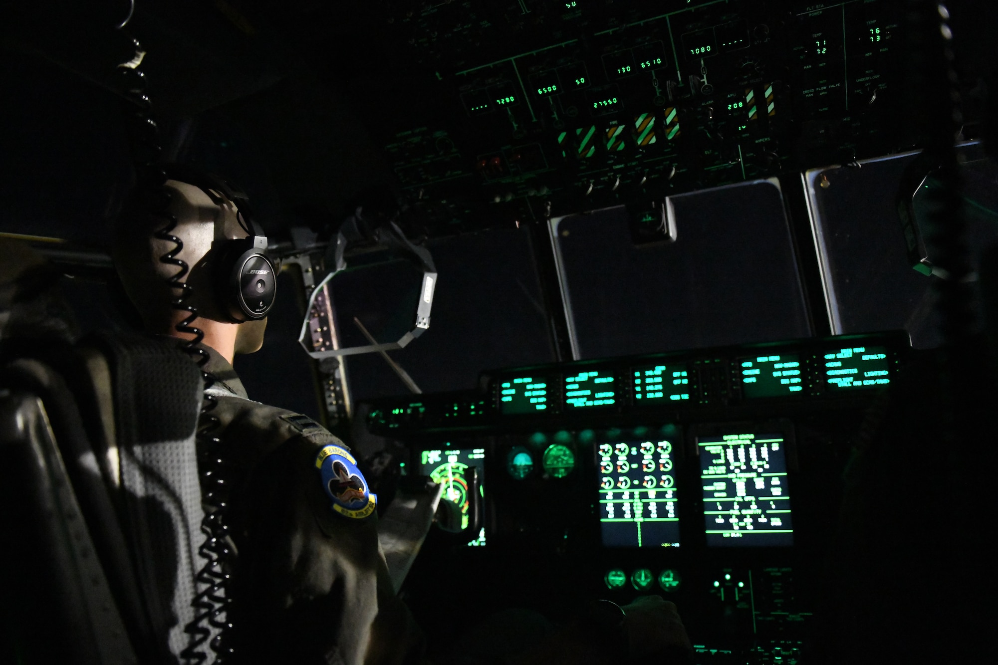 A man wears a headset while he flys a plane in the darkness of the night