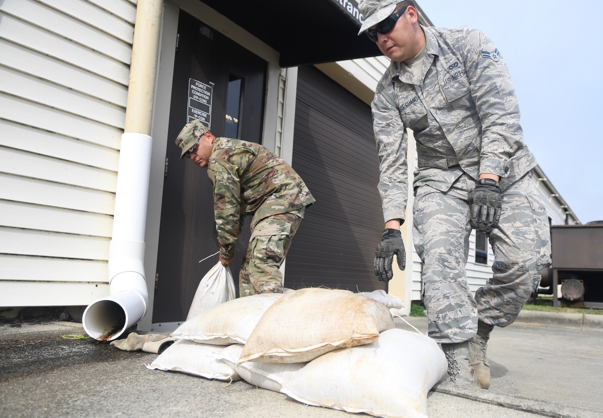Seymour Johnson Air Force Base, N.C. — SSgt Manuel Acuna and Airman 1st Class Torre Ruano, 4th Civil Engineer Squadron pavement and production specialists, stack sand bags Sept. 4, 2019, at Seymour Johnson Air Force Base, North Carolina in front of th 4th CE headquarters building. The 4th CES, to include equipment operators, electricians, plumbers, structural craftsman, heating, ventilation and air conditioning, and production technicians, are providing 24-hour response and recovery operations during and following Hurricane Dorian. (U.S. Air Force photo by Staff Sgt. Michael Charles)