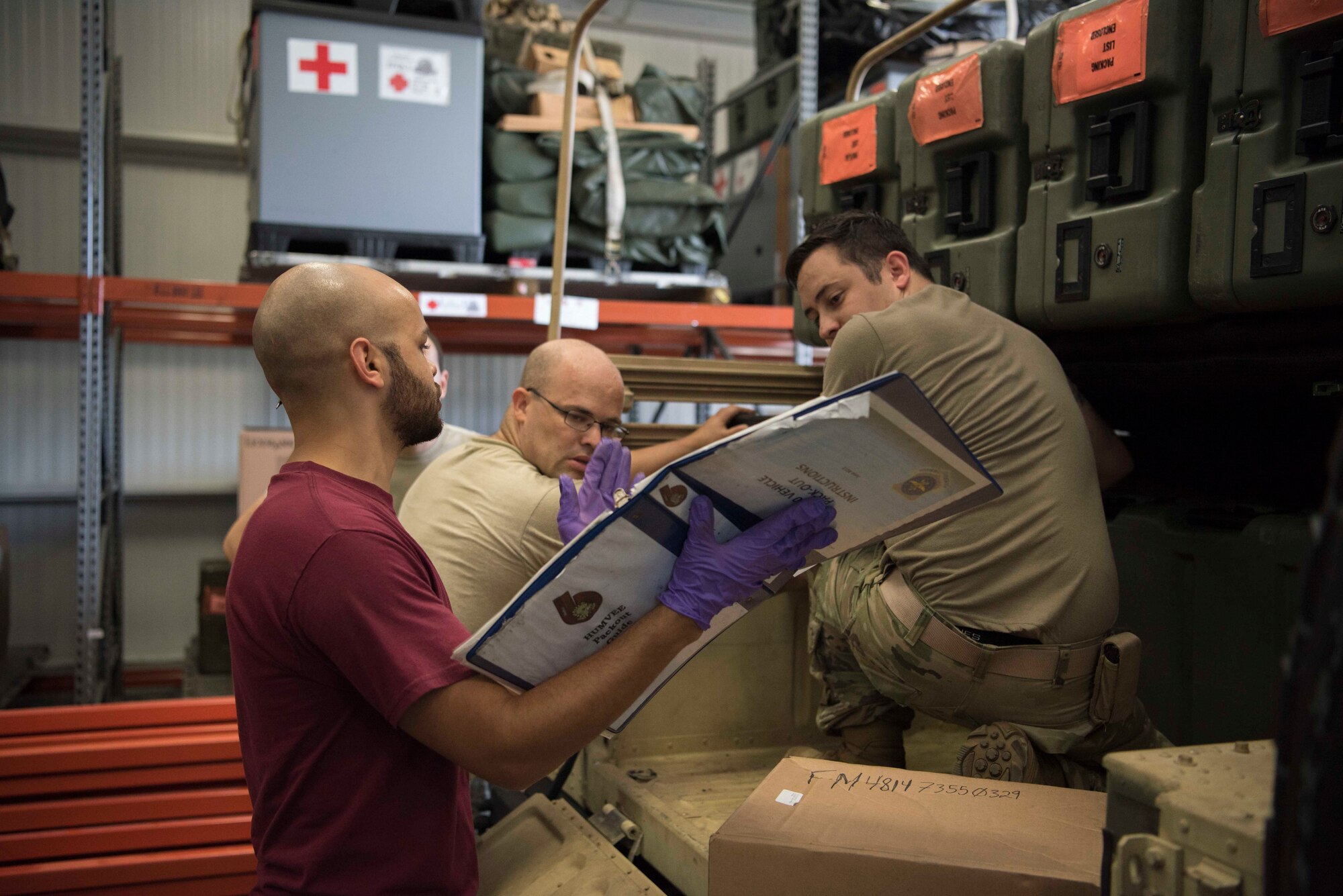 Chris Sadler, a government contractor, U.S. Air Force Master Sgt. Ursus Vargas, a 6th Medical Support Squadron (MDSS) medical material section chief, and U.S. Air Force Staff Sgt. Dustin Johnson, a 6th MDSS biomedical equipment technician, read a Humvee pack-out guide at MacDill Air Force Base Fla., Sept. 4, 2019. Pack-out guides provide the most efficient packing schemes to maximize space and resources. (U.S. Air Force Photo by Senior Airman Frank Rohrig)