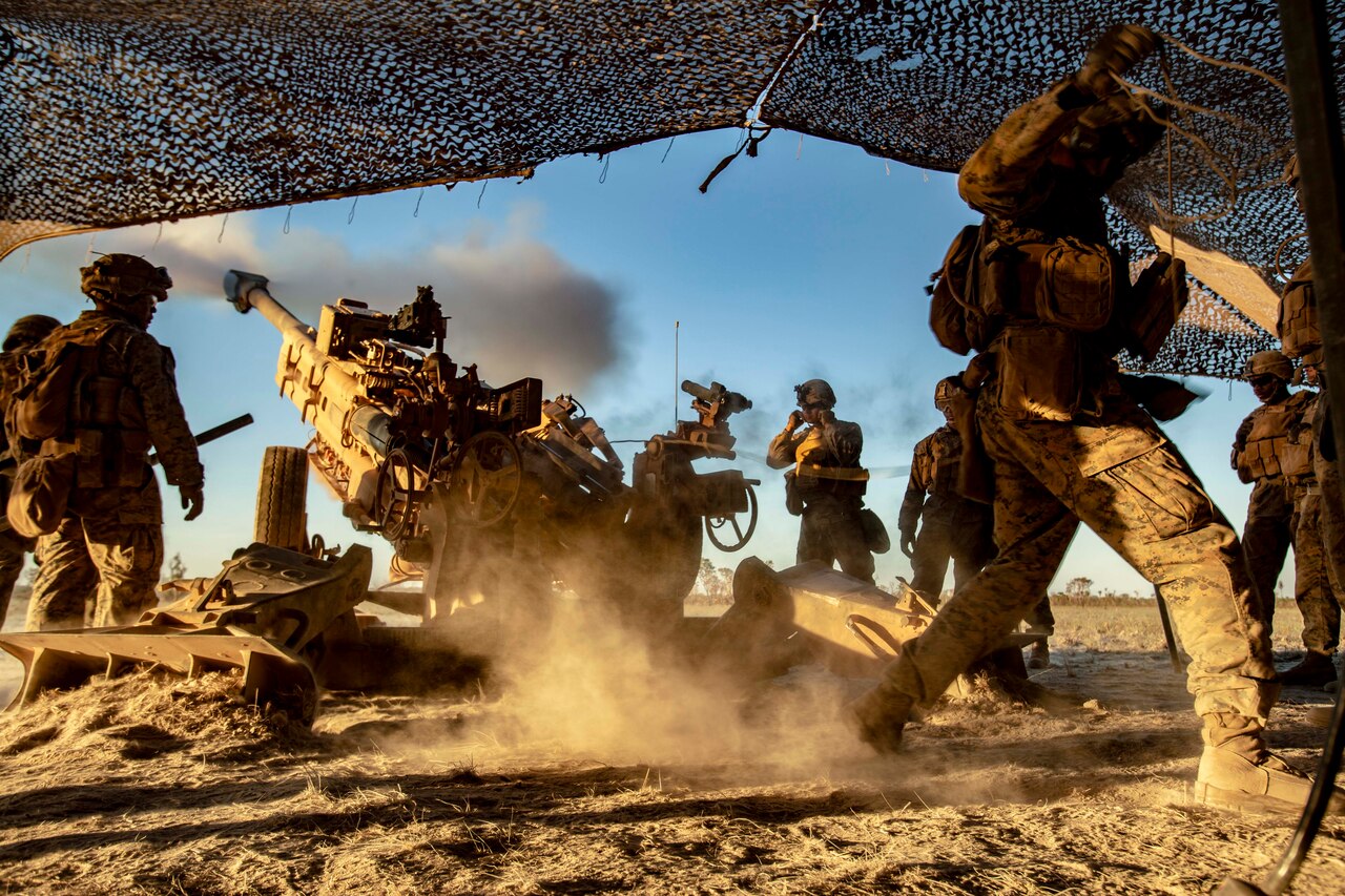 A group of Marines fire a howitzer.