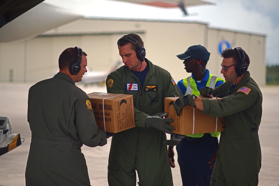 A Coast Guard C-130 crew unloads boxes of food in the Bahamas.