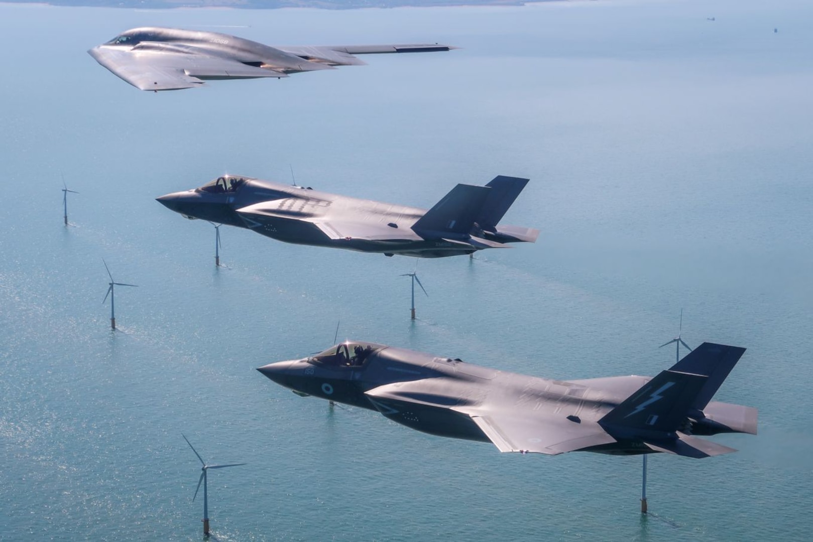 A U.S. Air Force B-2 Spirit, currently deployed to RAF Fairford in Gloucestershire, England, flies above the English countryside near Dover with two RAF F-35 jets. This is the first time UK F-35s have conducted training with the stealth bomber.