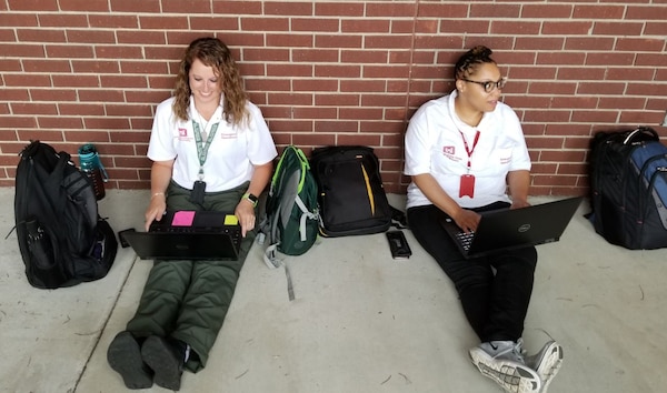 Lauren Beasley, Action officer (left) and Alex Duckett, Mission Specialist (right), working at the South Carolina State Emergency Operations Center in Columbia making use of the front porch as they wait for an all-hands meeting to begin. Power Team members show great flexibility and patience as they prepare to help those affected by Hurricane Dorian.