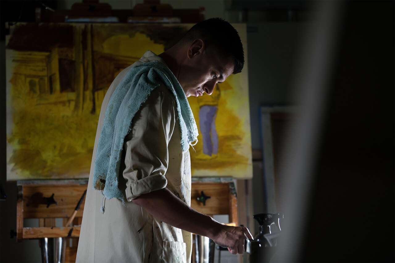 Artist applies paint to palette.