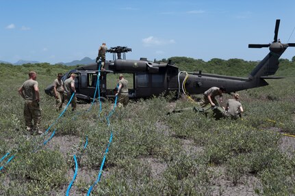 Soldiers from the 1st Battalion 228th Aviation Regiment connect sling cables to a UH-60 Blackhawk for it to be carried from an austere riverbank to Liberia Airport in Costa Rica July 29, 2019. During a mission to support the USNS Comfort, the UH-60 crew performed a precautionary landing in an austere environment in Costa Rica. After inspecting the Blackhawk, the crew determined that aircraft was not safe to fly. Joint service members from Joint Task Force - Bravo worked together, with the assistance of a C-17 Globemaster III from U.S. Transportation Command, to return the broken helicopter back to Soto Cano. (U.S. Air Force photo by Tech. Sgt. Eric Summers Jr.)