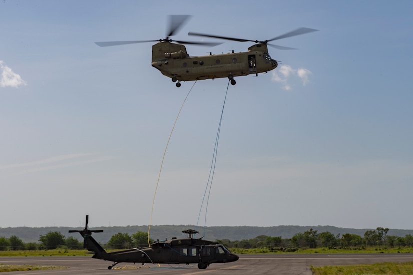 A CH-47 Chinook from the 1st Battalion 228th Aviation Regiment places a broken UH-60 on the flightline on Liberia Airport, Costa Rica, July 29, 2019. During a mission to support the USNS Comfort, the UH-60 crew performed a precautionary landing in an austere environment in Costa Rica. After inspecting the Blackhawk, the crew determined that aircraft was not safe to fly. Joint service members from Joint Task Force - Bravo worked together, with the assistance of a C-17 Globemaster III from U.S. Transportation Command, to return the broken helicopter back to Soto Cano. (U.S. Air Force photo by Tech. Sgt. Eric Summers Jr.)