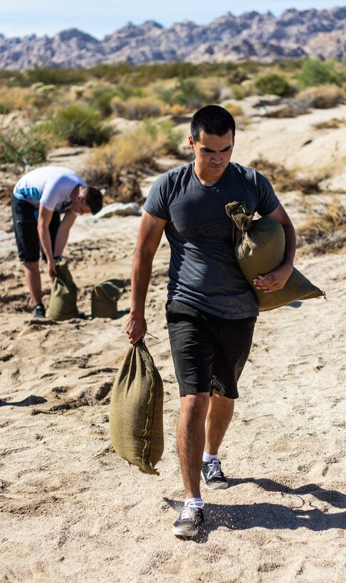U.S. Marine Pfc. Andy Munoz with 3rd Battalion, 4th Marine Regiment carries sandbags in Twentynine Palms, Calif., July 27, 2019. The Marines and sailors volunteered to assist a veteran and current government service employee with repairing his home after it was damaged by a flash flood. (U.S. Marine Corps photo by Pfc. Shane T. Beaubien)