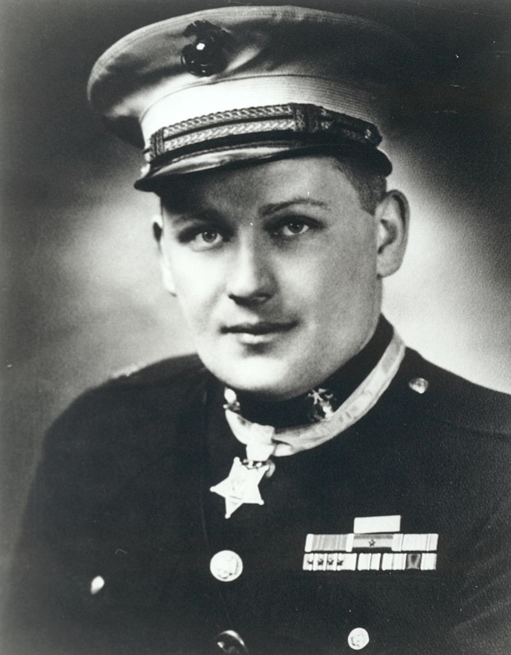A Marine Corps major in full dress uniform wears the Medal of Honor around his neck.