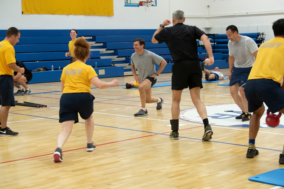 Men and women exercise in a gym.