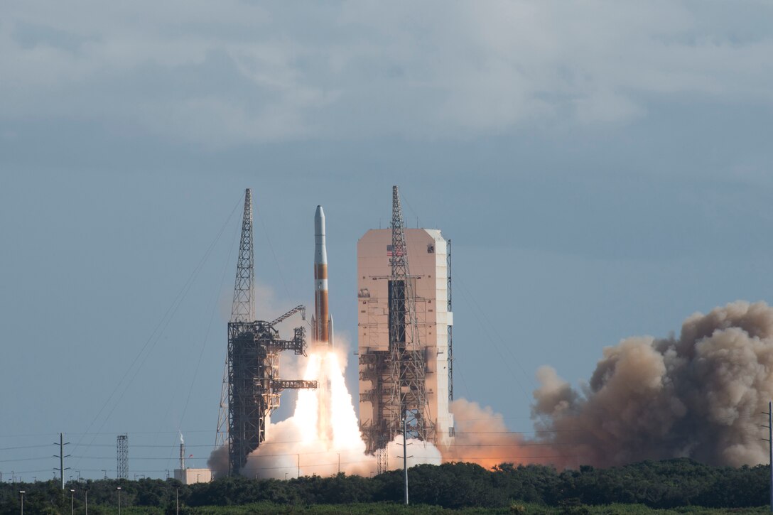 Against a gray-blue sky, a rocket leaves its launch tower.