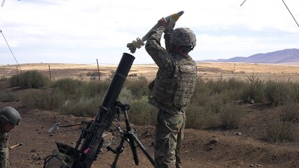 A Soldier from Headquarters and Headquarters Company, 2nd Battalion, 130th Infantry Regiment, based in Marion, Illinois, prepares to load a 120mm mortar shell during Rising Thunder 19.