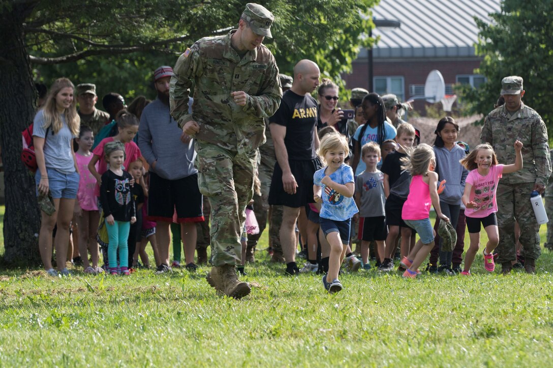 A service member runs next to a child during an event.