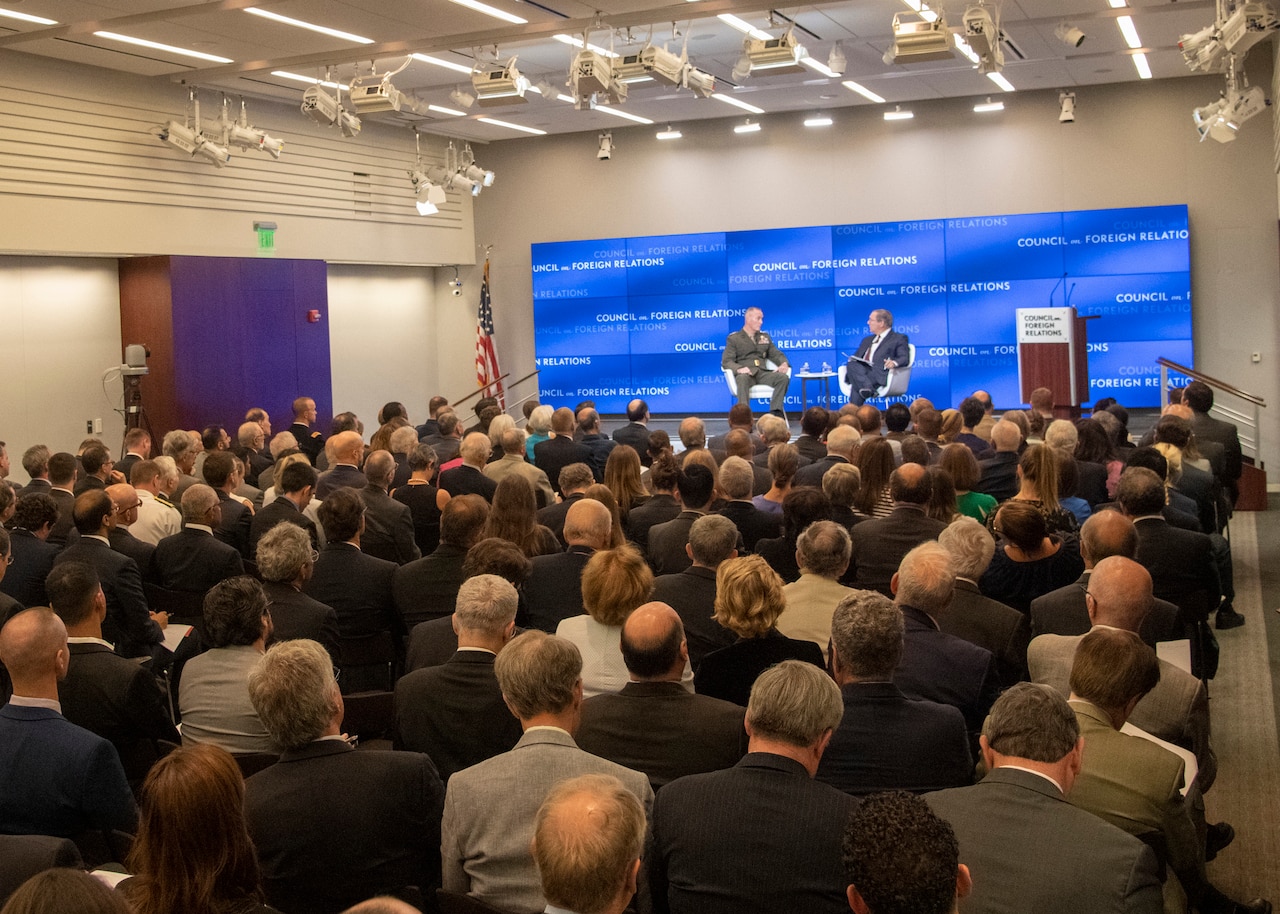 Two men speak on stage.