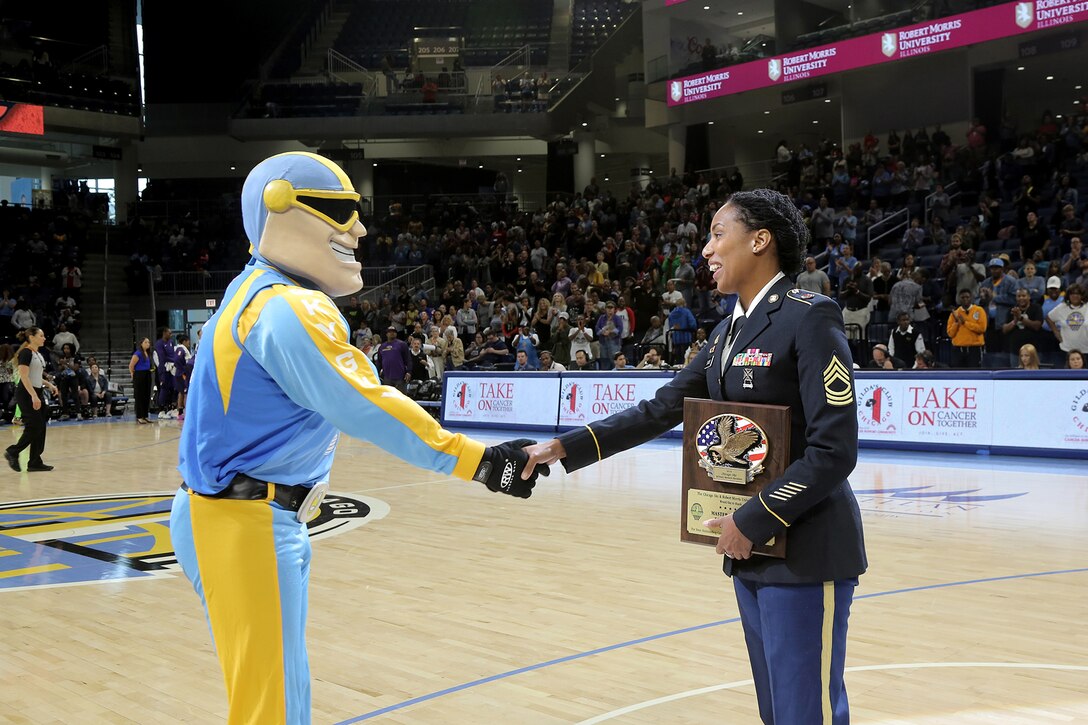 Sky Guy, the Women’s National Basketball Association’s Chicago Sky team mascot, shakes hands with U.S. Army Reserve Master Sgt. Ebony Evans after honoring her for her service during the Chicago Sky’s final home game, of the regular season, at the Wintrust Arena in Chicago, Illinois, September 1, 2019.