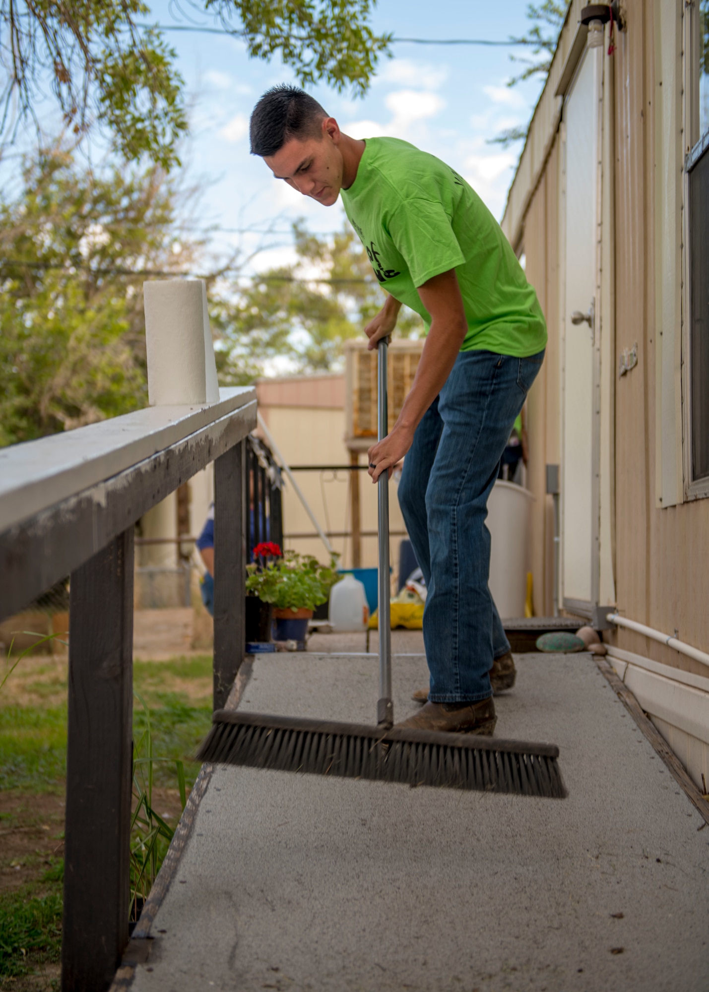 Airman 1st Class Jacob Boren, 9th Aircraft Maintenance Squadron MQ-9 Reaper weapons load crew member, sweeps a porch, Sept. 6, 2019, at a residence in Alamogordo, N.M. Day of Caring volunteers performed various tasks, such as home repairs and yard work, at pre-determined job sites for individuals who are either unable to accomplish the tasks themselves or do not the resources to do so. (U.S. Air Force photo by Airman 1st Class Kindra Stewart)