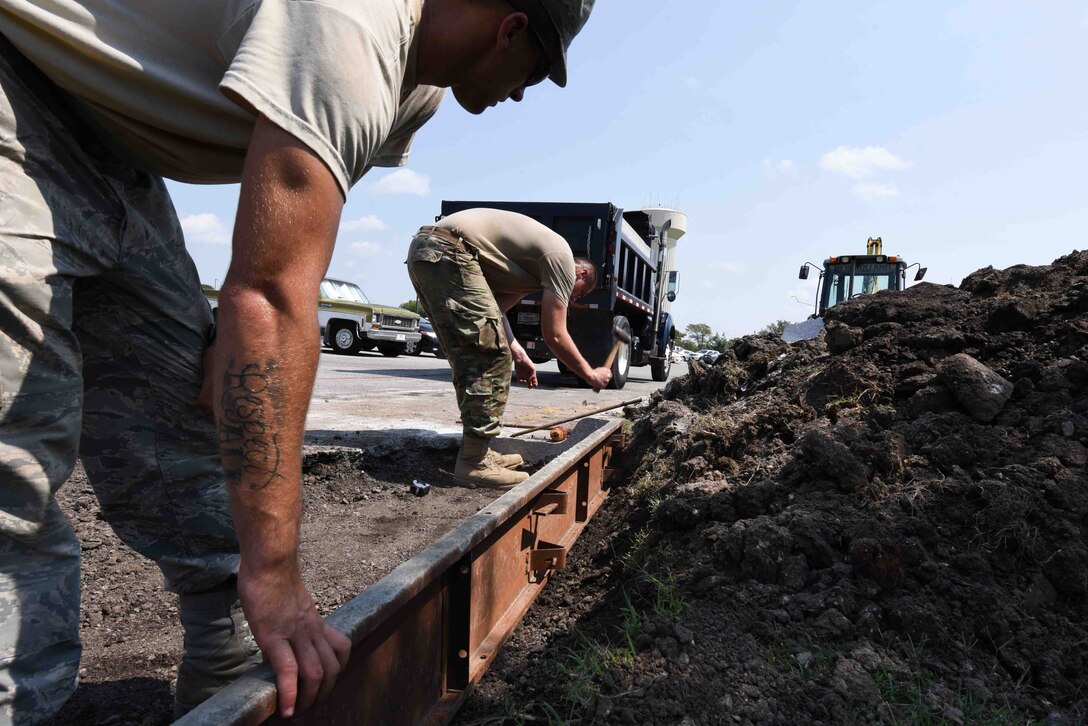 Senior Airman Thomas Duffy, 22nd Civil Engineering Squadron pavement and equipment journeyman, and Airman 1st Class Koby Disotell, 22nd CES pavement and equipment apprentice, place concrete forms Sept. 4, 2019, at McConnell Air Force Base, Kan. The forms will be sprayed with oil to prevent the concrete from sticking. The forms will enclose the concrete until it hardens and takes shape. (U.S. Air Force photo by Airman 1st Class Alexi Myrick)